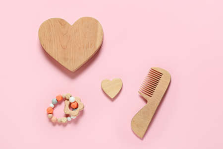 Wooden hearts and accessories for baby on pink background