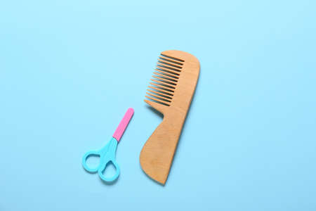 Wooden hair comb and scissors for baby on blue backgroundの写真素材