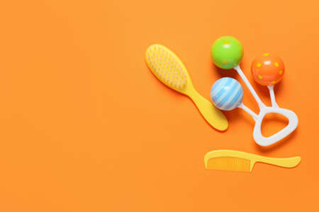 Hair brush, comb and rattle on color background