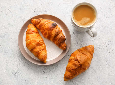 Plate with delicious croissants and cup of coffee on white backgroundの写真素材