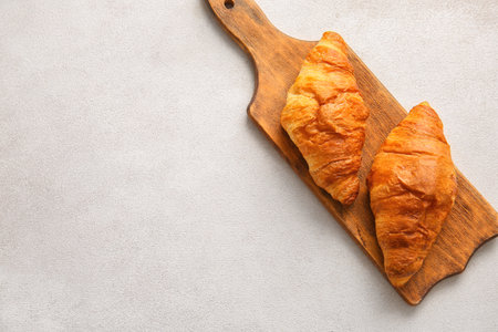 Wooden board with delicious croissants on white backgroundの写真素材