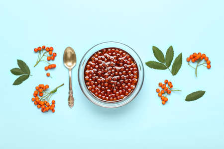 Composition with bowl of tasty rowan jam and berries on blue backgroundの写真素材