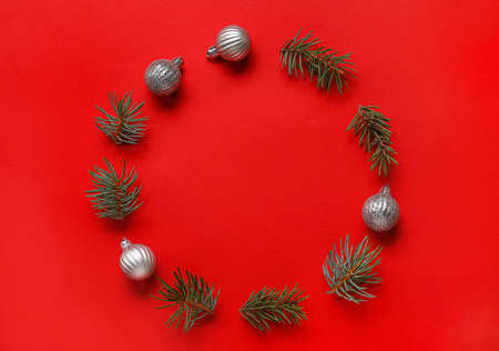 Frame made of fir branches and Christmas balls on color backgroundの写真素材