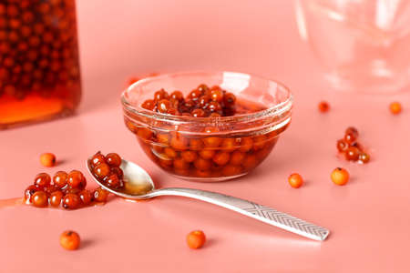 Glass bowl with delicious rowan jam on color background