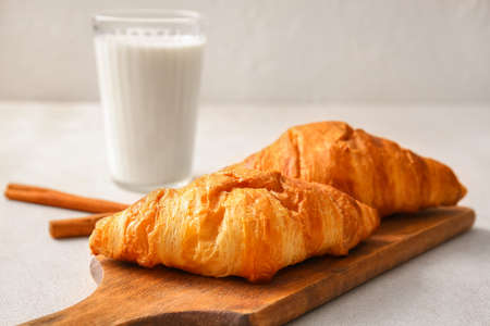 Wooden board with delicious croissants on white backgroundの写真素材