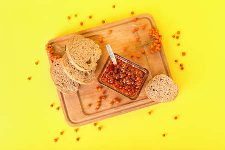 Board with delicious rowan jam and bread on yellow backgroundの写真素材