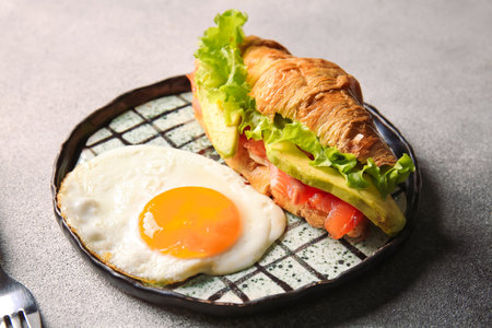 Plate of delicious croissant sandwich with egg on light backgroundの写真素材