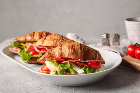 Plate with delicious croissant sandwiches on gray backgroundの写真素材