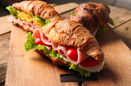 Board with delicious croissant sandwiches on tableの写真素材