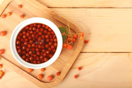 Bowl with healthy rowan berry jam on wooden background