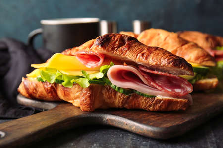 Wooden board with delicious croissant sandwiches on black backgroundの写真素材