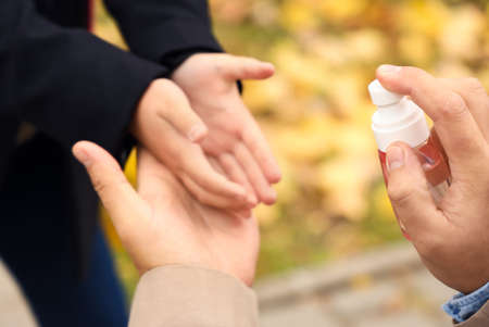 Man disinfecting hands of his little daughter before school, closeupの写真素材