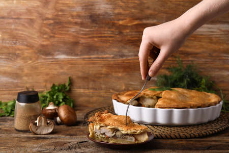 Woman eating piece of tasty chicken pot pie on wooden backgroundの写真素材