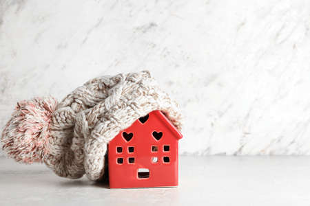 House figure with warm hat on light background. winter conceptの写真素材