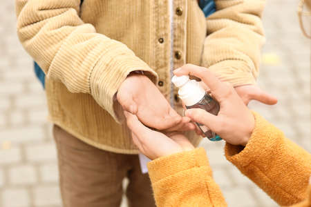 Woman disinfecting hands of her little son before school, closeupの写真素材