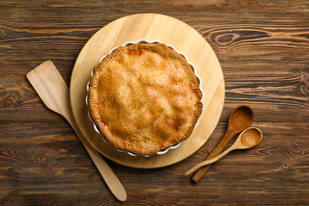 Baking dish with tasty chicken pot pie on wooden background