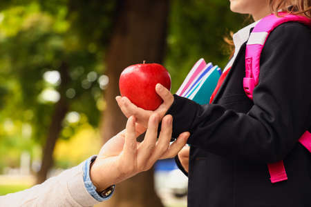 Man giving his little daughter an apple before schoolの写真素材