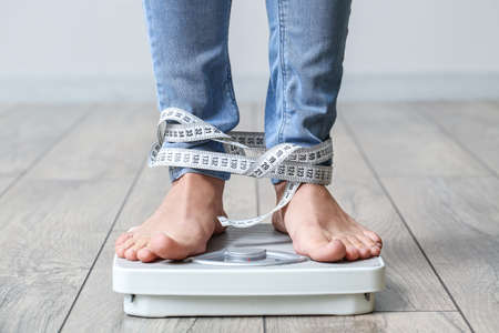 Young woman with anorexia measuring her weight at homeの写真素材