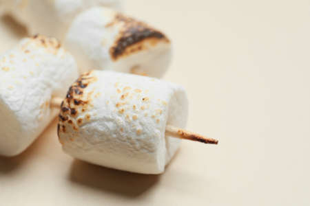 Skewers with tasty grilled marshmallows on light background, closeup