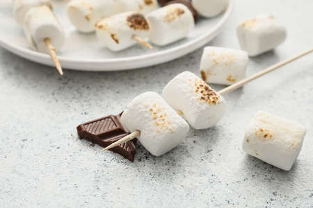 Skewers with tasty grilled marshmallows on light backgroundの写真素材