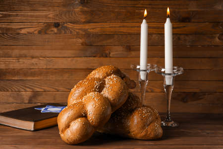 Traditional challah bread with glowing candles and Torah on wooden background. Shabbat Shalomの写真素材
