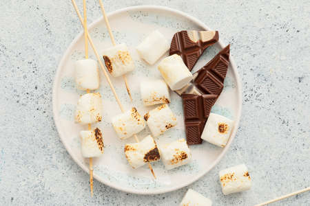 Plate of tasty grilled marshmallows with chocolate on light backgroundの写真素材