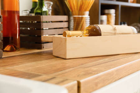 Box with bottle of wine on wooden table top in kitchen