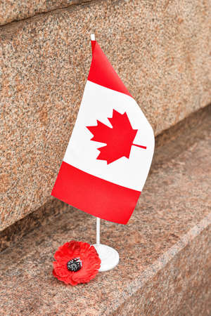 Poppy flower and flag of Canada on stone monument. Remembrance Dayの写真素材