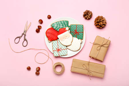 Plate with delicious Christmas cookies and gifts on color background
