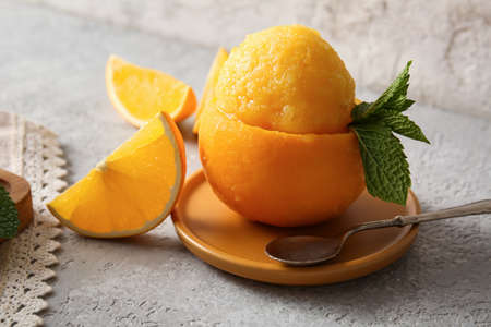 Board with tasty ice cream in orange peel on gray backgroundの写真素材
