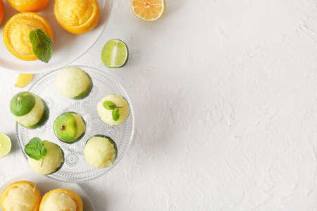 Plates with tasty ice creams in citrus fruit peels on light backgroundの写真素材