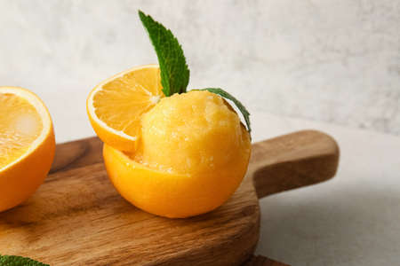 Board with tasty ice cream in orange peel on light backgroundの写真素材