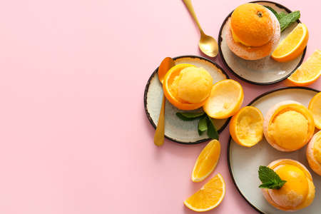 Plates with tasty ice creams in orange peels on color background