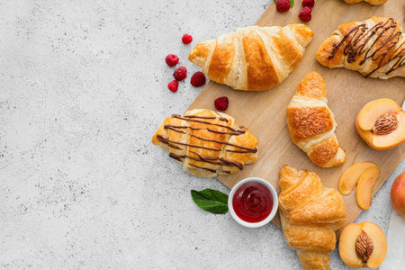 Wooden board of delicious croissants with fruits on light backgroundの写真素材
