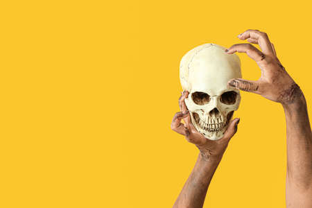 Hands of zombie with skull on color backgroundの写真素材