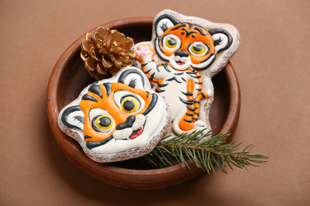 Bowl with cute cookies in shape of tiger and New Year decor on color backgroundの写真素材