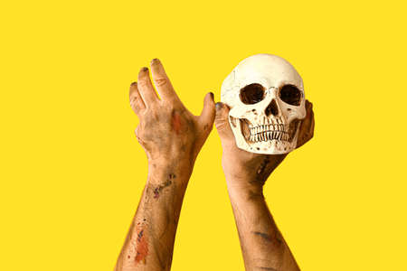 Hands of zombie with skull on color backgroundの写真素材
