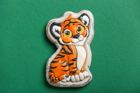 Cute cookie in shape of tiger for New Year 2022 on color background