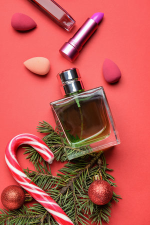 Perfume bottle, fir tree branch, candy cane and decorative cosmetics on color backgroundの写真素材