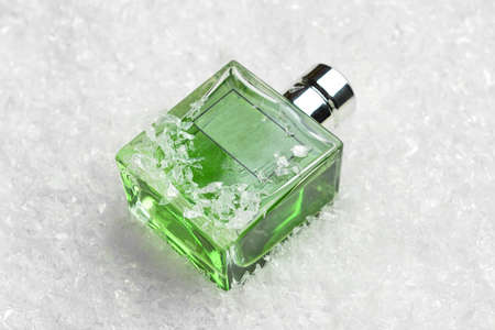 Bottle of perfume in snow on light backgroundの写真素材