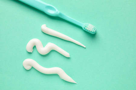 Samples of toothpaste and brush on turquoise background, closeupの写真素材