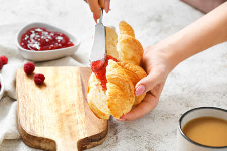 Woman with tasty croissant and raspberry jam