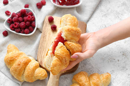 Woman with tasty croissant and raspberry jam