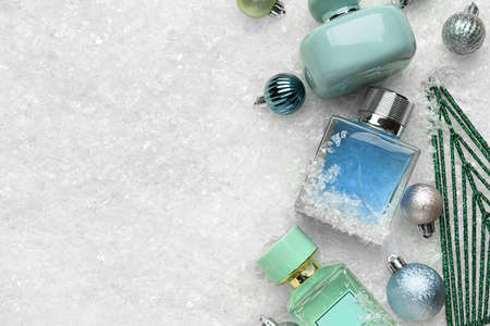 Different perfume bottles and Christmas decor on snow backgroundの写真素材