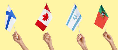 Hands with flags of different countries on yellow background