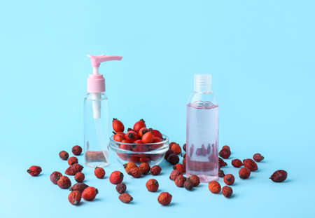Bottles of cosmetic products and rose hip berries on blue backgroundの写真素材