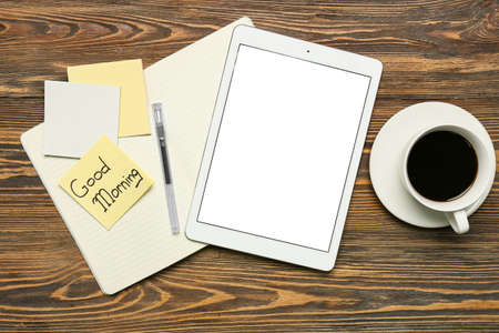 Composition with tablet computer, cup of coffee, stationery supplies and sticky note with text GOOD...