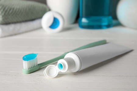 Opened tube with toothpaste and toothbrush on white wooden tableの写真素材
