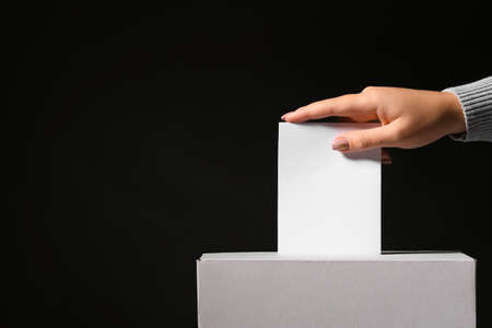 Voting woman near ballot box on dark backgroundの写真素材