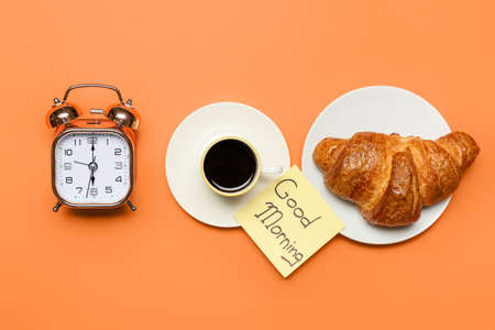 Composition with alarm clock, breakfast and sticky note with text GOOD MORNING on color backgroundの写真素材